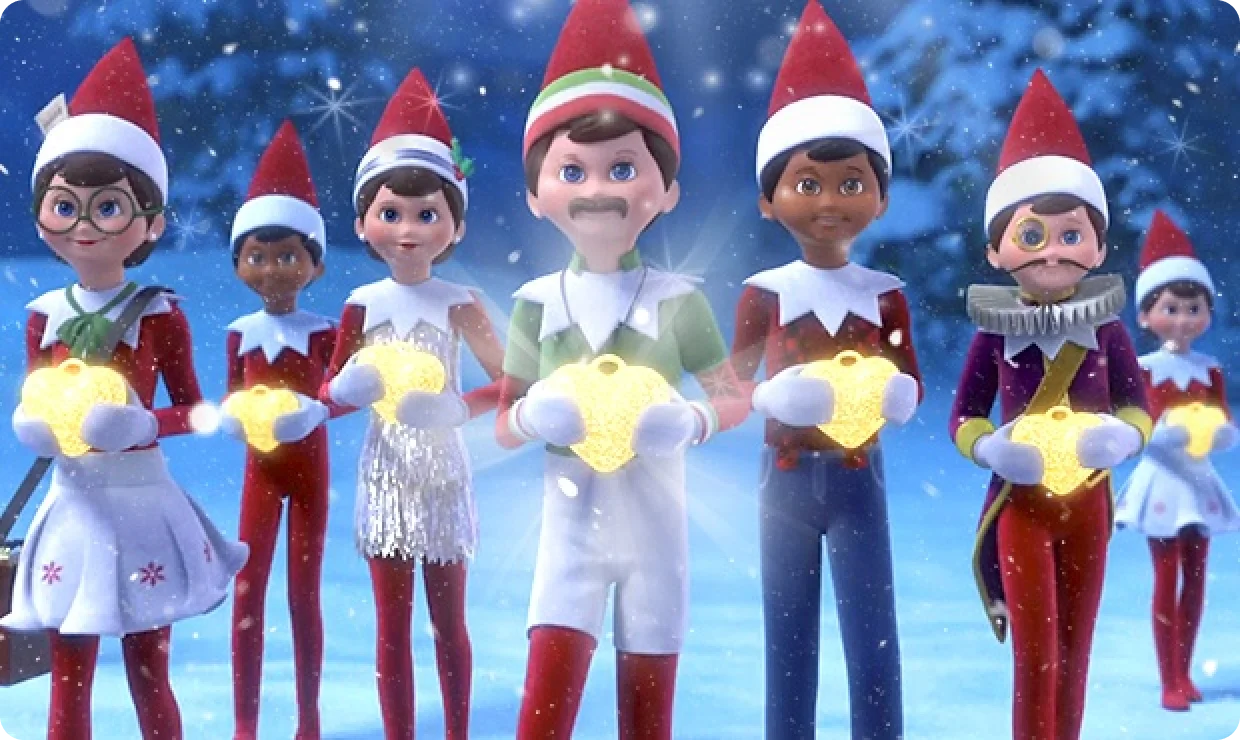 A line of Scout Elves from the knees up holding glowing heart charms to their chests. The elves include Newsey, Tinsel, Gym Dandy, Timber, and Scout Elf Joe. They are standing in snow with snow-covered pine trees behind them.