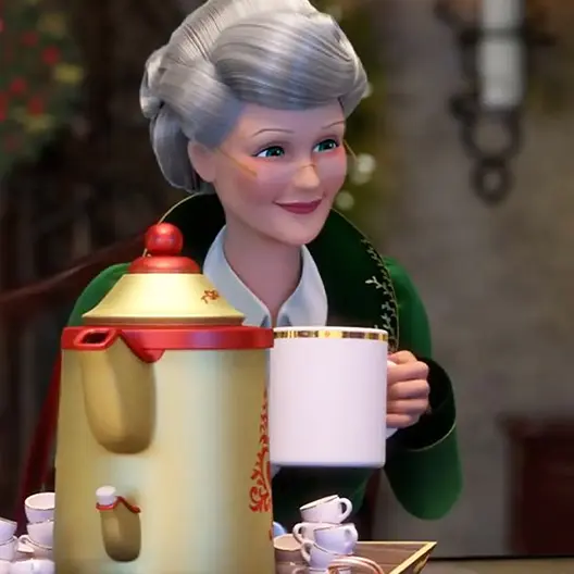 Mrs. Claus in her green coat and white collared shirt from the chest up. She is standing behind a tray holding a large gold and red kettle and stacks of elf-sized white and gold mugs. In her hand is a human-sized mug. Behind her is a red, gold, and green Christmas wreath, a gray wall and a black sconce with a white candle inside.