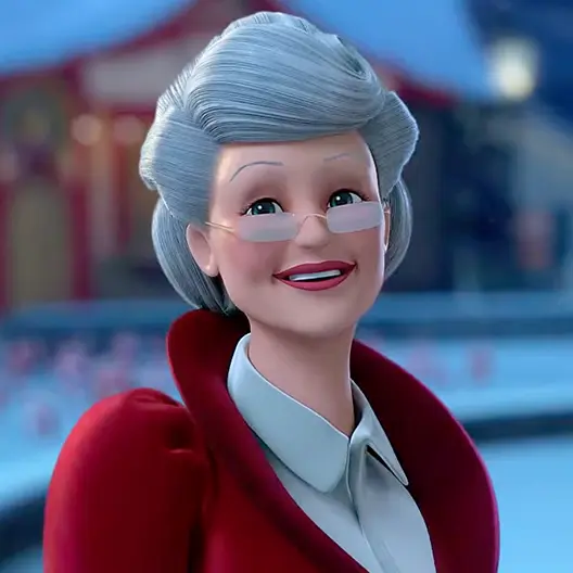 Mrs. Claus in her red coat and white collared shirt from the chest up. She is standing in the City Center of the North Pole. Behind her is a blurred red and tan building, a lamppost, a stone wall, a ground covered with snow, and about a dozen elves standing on the ground.
