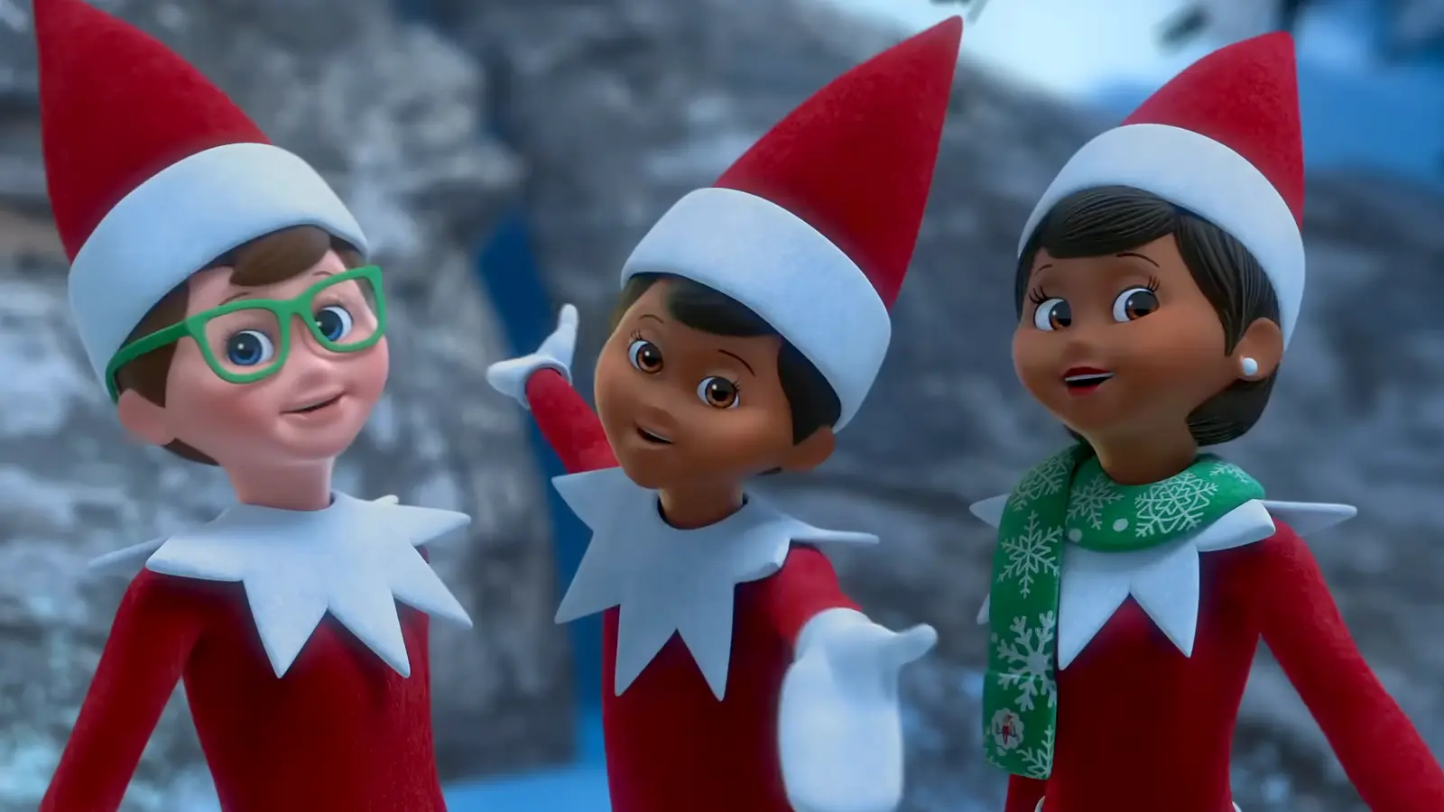 3 smiling Scout Elves from the waist up in front of a winter mountain scene. From left to right there is a light skinned boy elf with green glasses, a dark skinned boy elf with his arms spread open to the front and back, and a girl elf with dark skin with a green scarf with white snowflakes and The Elf on the Shelf logo on it.