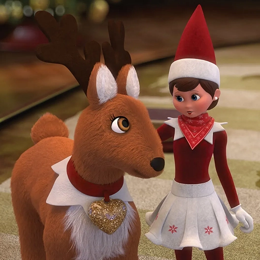 An Elf Pets Reindeer and Macie the Scout Elf looking at one another and standing atop of the table in Santa's Strategy Room. Macie has her arm on the reindeer's back.