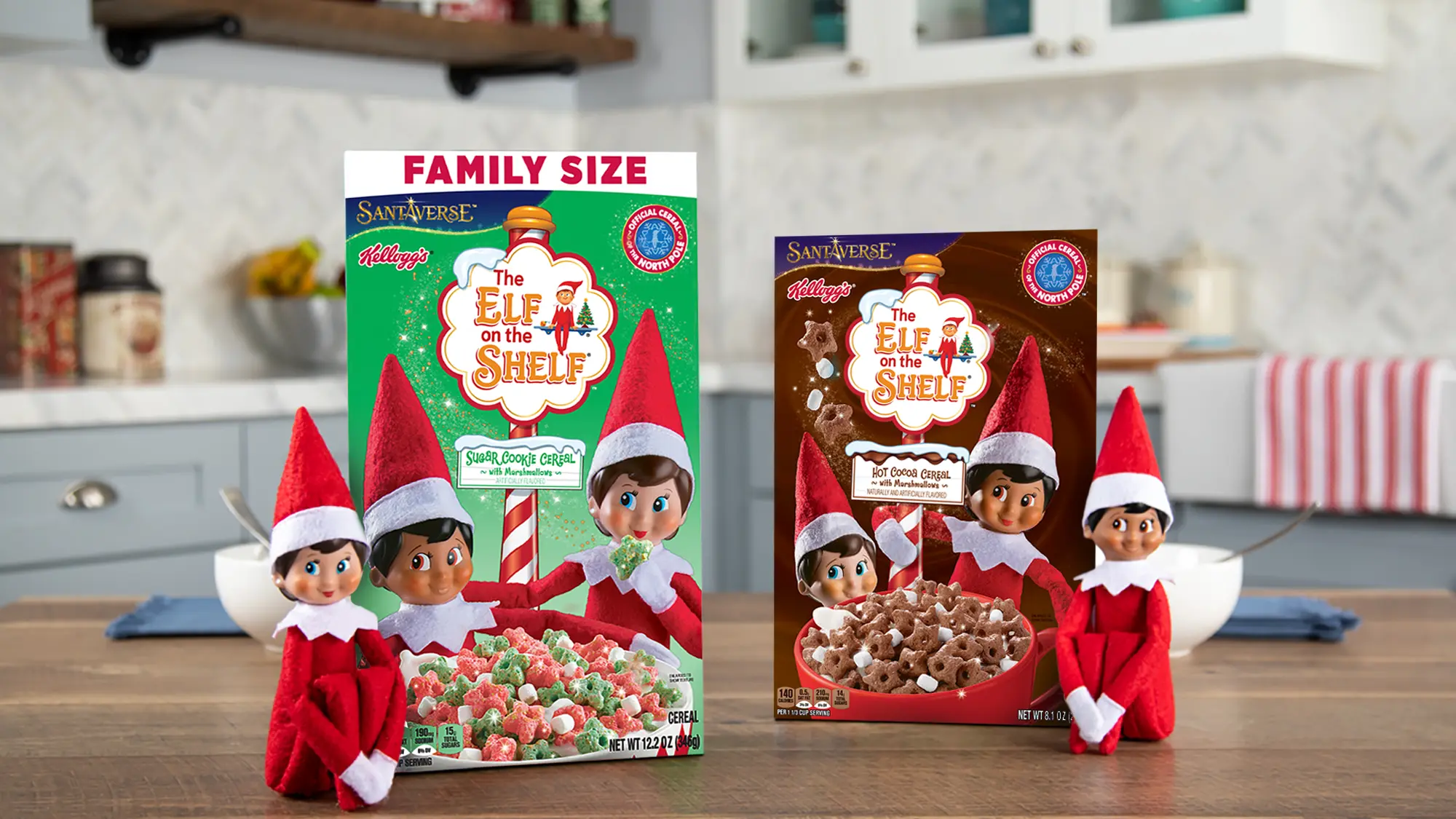 Box of Kellogg's, Santaverse, and The Elf on the Shelf branded Sugar Cookie Cereal and box of Hot Cocoa Cereal sitting on a kitchen counter. Sitting in front of the boxes are two Scout Elves.