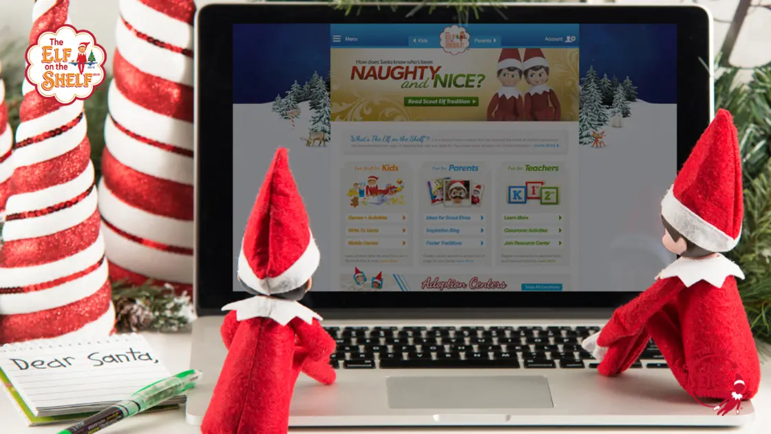 Two scout elves watching a laptop on a desk next to a notepad that reads "dear santa"