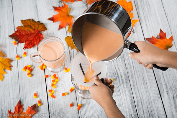Pot of hot cocao being poured into cup