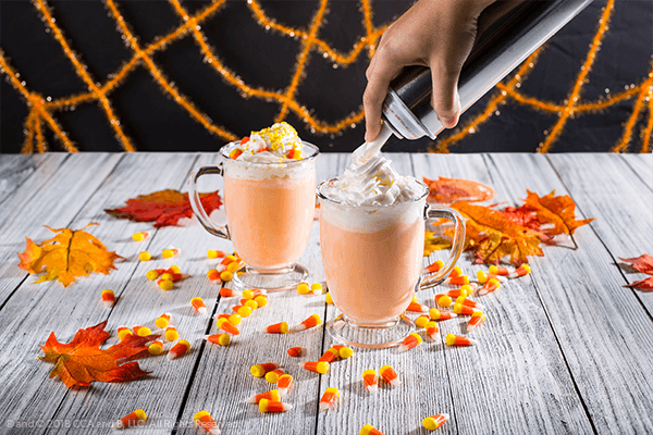 Two glasses of hot cocoa and candy corn with whipped cream