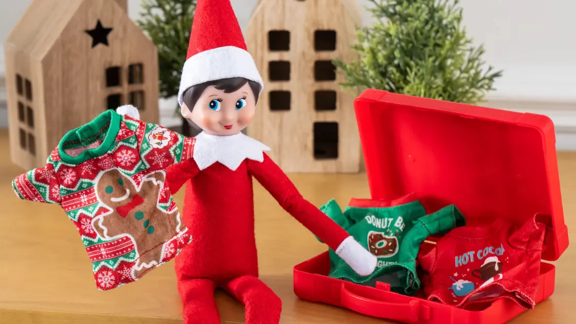 Scout Elf packing clothes into red suitcase while smiling