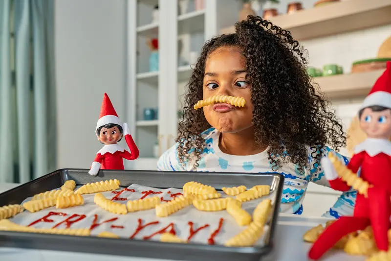 Two elf scouts with young girl making french fries.