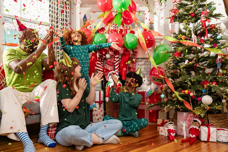 family of four celebrating by Christmas tree.