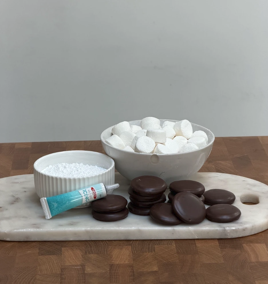 Biscuits arranged on a lined baking tray while marshmallows are prepared
