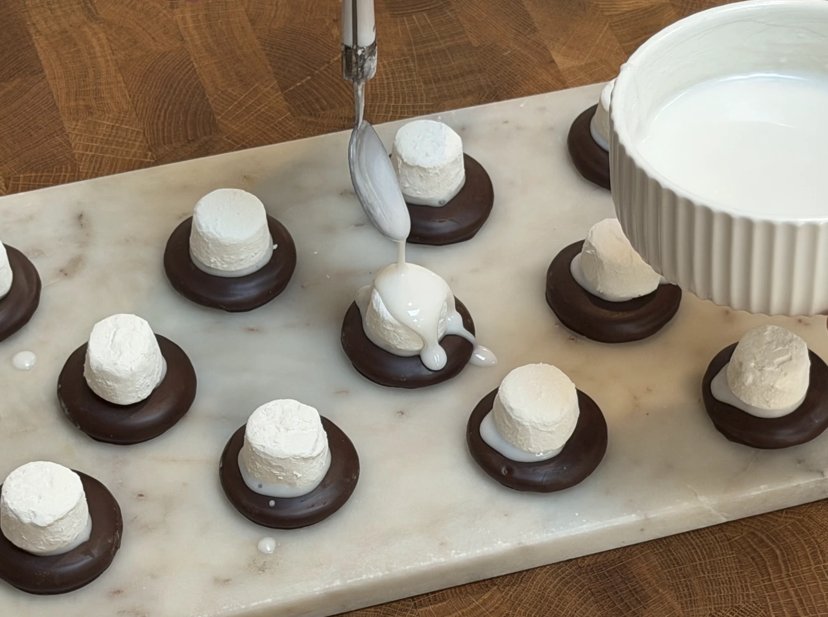 Icing dripping over marshmallows while the biscuits rest