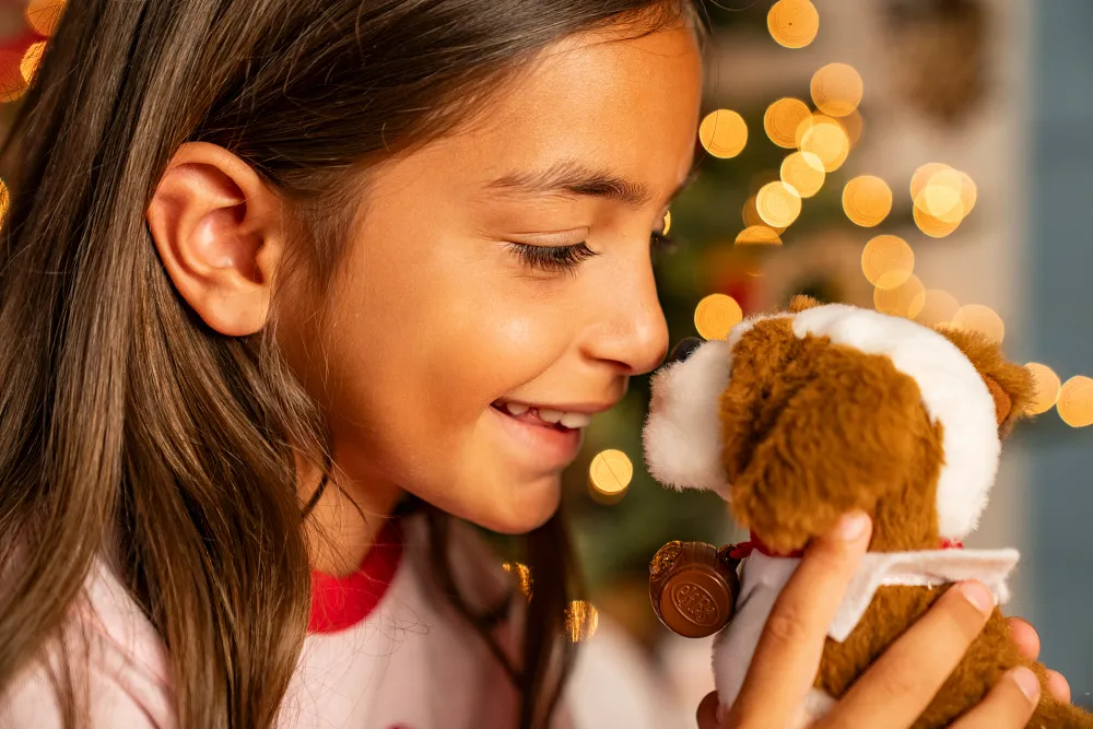 Child holding and smiling at Elf Pets Saint Bernard plush, a cuddly Santaverse companion that encourages kindness and emotional support for children