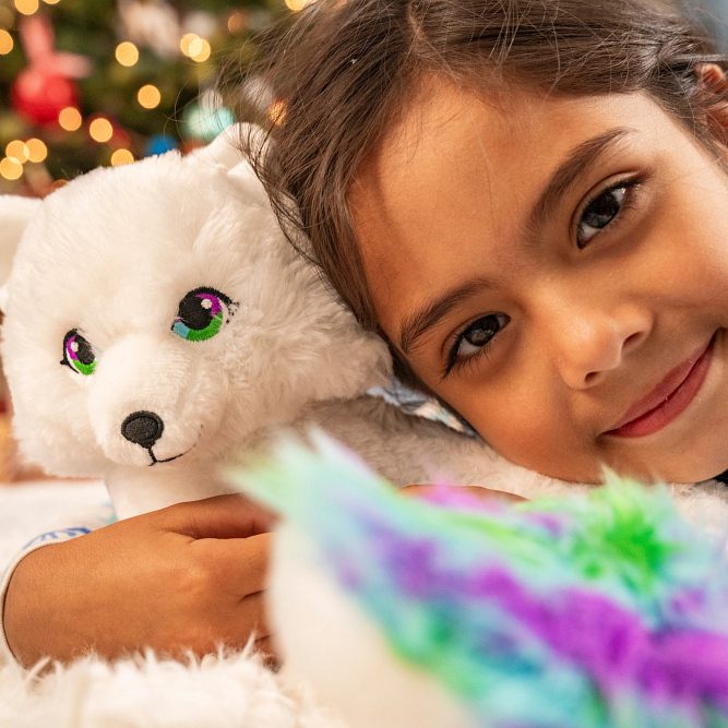 Noorah plush toy being held by young girl