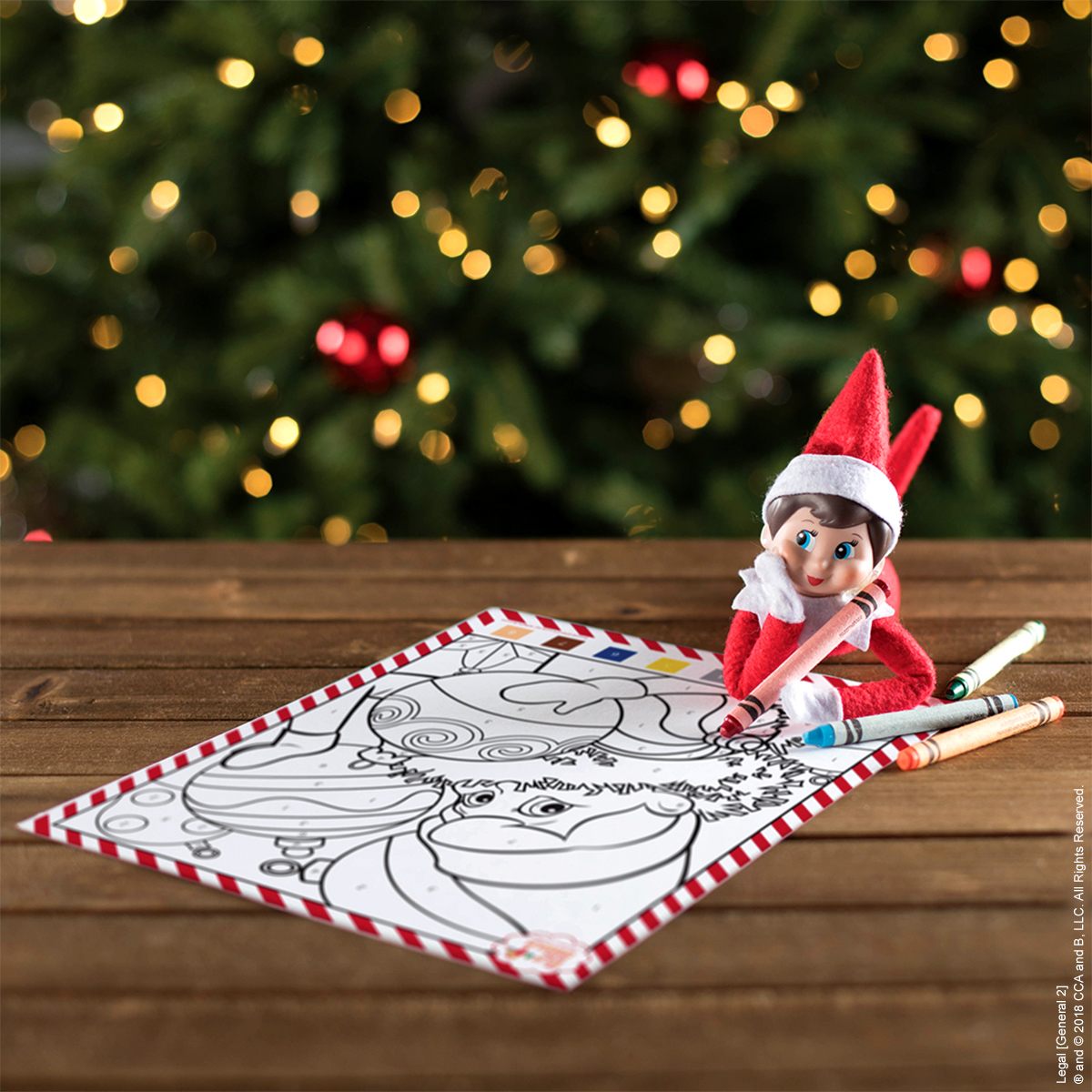 A Scout Elf lies on the floor colouring a Santa picture beside glowing Christmas tree lights.