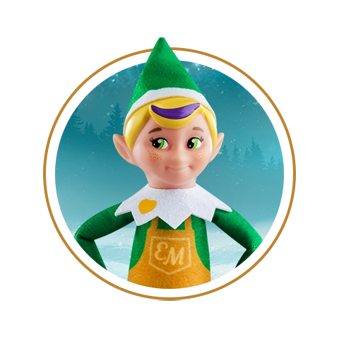 Elf Mates® Toy Maker stands with his hands on his hips. He is framed in a circle with a wintery background as well as a golden stroke that also encloses him.